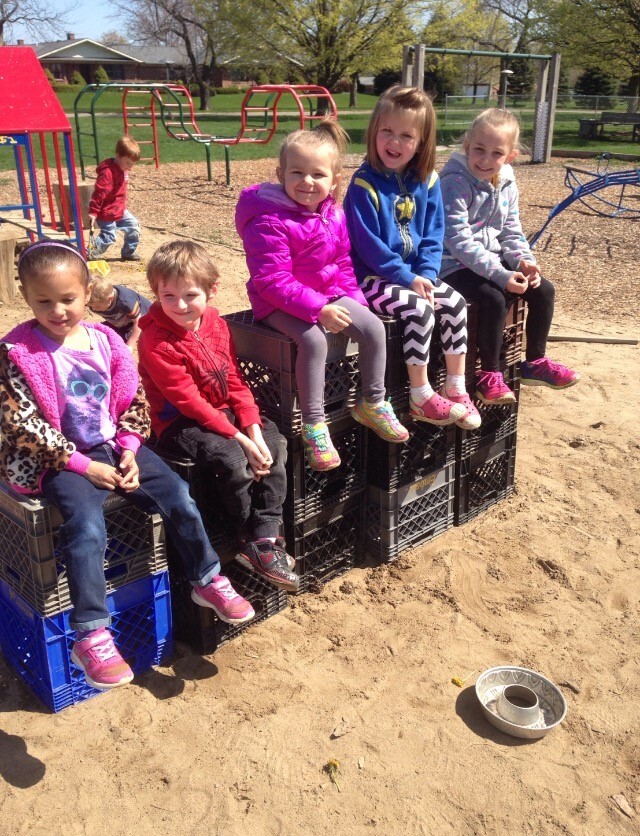 Five children sitting on crates in a playground