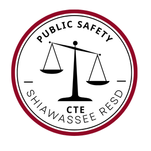 The scales of justice in black surrounded by the words Public Safety, CTE, and Shiawassee RESD